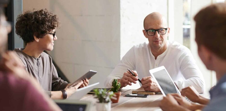 Group of professionals engaged in a brainstorming session around a table in a contemporary office space.